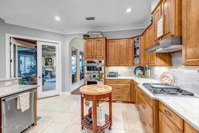 kitchen with light tile patterned floors, stainless steel appliances, tasteful backsplash, visible vents, and under cabinet range hood