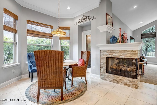 dining area with crown molding, a stone fireplace, baseboards, and tile patterned floors