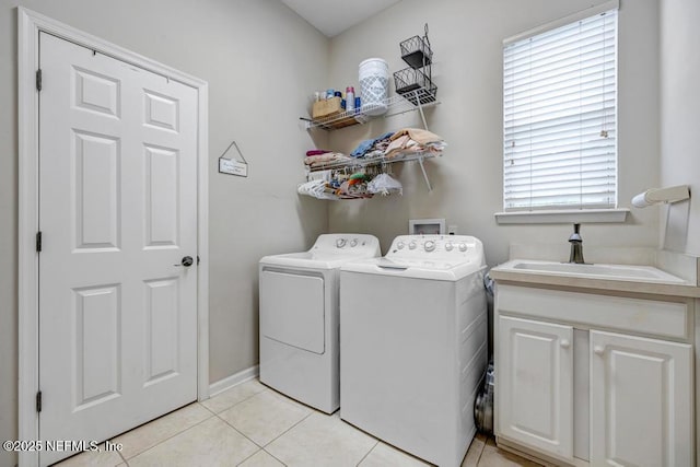 laundry area featuring light tile patterned floors, washing machine and dryer, cabinet space, and a sink