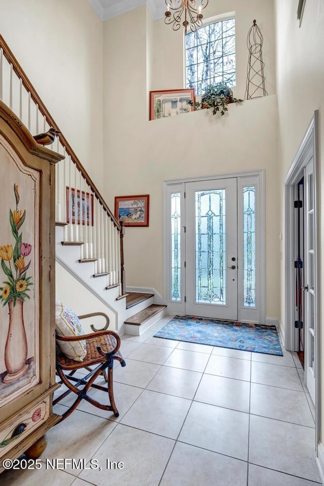 entrance foyer featuring a notable chandelier, stairway, a high ceiling, and tile patterned floors