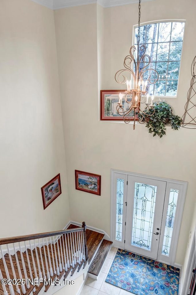 foyer entrance featuring light tile patterned floors, stairs, a towering ceiling, and an inviting chandelier