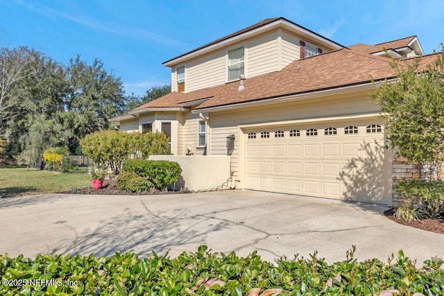 view of front of property with concrete driveway and roof with shingles