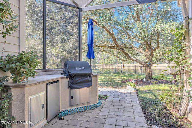 view of patio / terrace with exterior kitchen, a fenced backyard, and a lanai