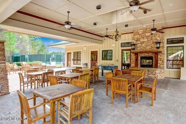 dining room with an outdoor stone fireplace and ceiling fan with notable chandelier