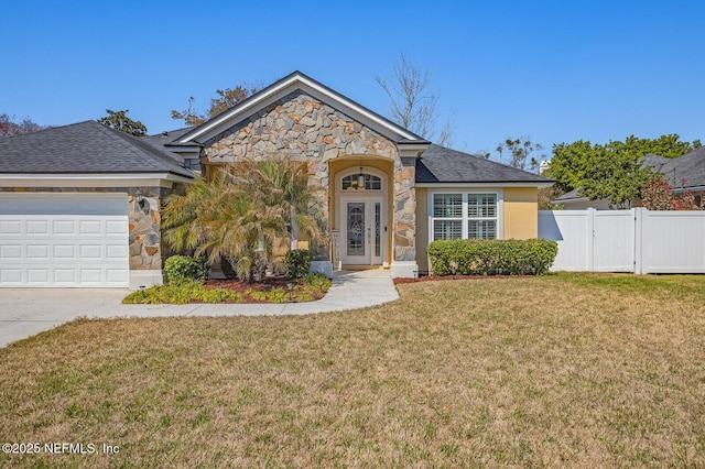 view of front facade with an attached garage, fence, stone siding, a gate, and a front yard