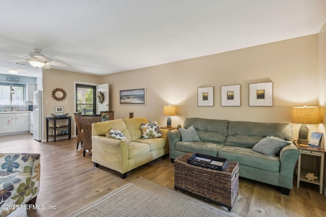 living room with ceiling fan and light wood-type flooring