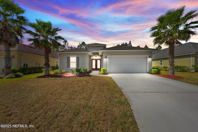 prairie-style house with french doors, stucco siding, concrete driveway, an attached garage, and a front yard