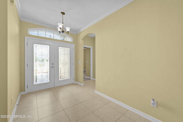 entryway with arched walkways, crown molding, an inviting chandelier, light tile patterned flooring, and baseboards