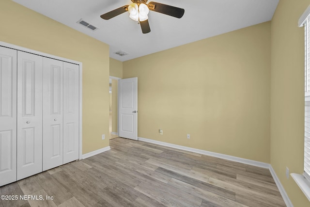 unfurnished bedroom with light wood-style flooring, a closet, visible vents, and baseboards