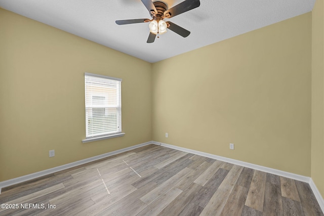 unfurnished room with a ceiling fan, baseboards, and wood finished floors