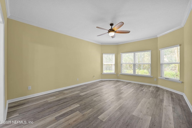 spare room featuring baseboards, wood finished floors, and crown molding