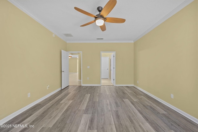 unfurnished bedroom with crown molding, visible vents, ensuite bath, wood finished floors, and baseboards