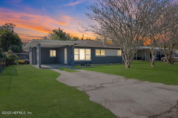 ranch-style house featuring concrete driveway, a carport, a front yard, and fence