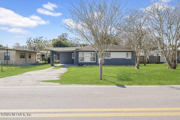 view of front of home featuring an attached carport, driveway, a front lawn, and fence