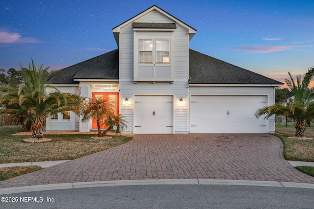 view of front of property featuring a shingled roof and decorative driveway