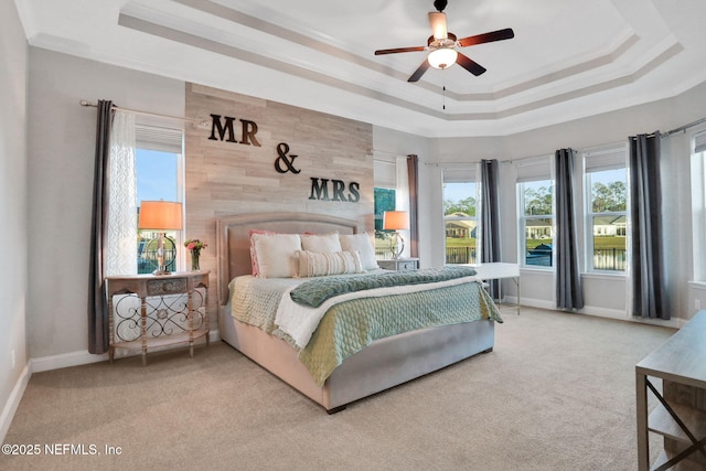 carpeted bedroom with a ceiling fan, baseboards, a raised ceiling, and crown molding