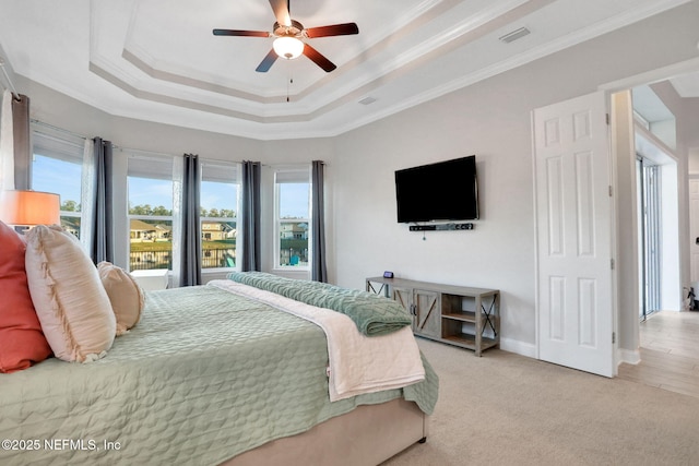 bedroom with a raised ceiling, light colored carpet, crown molding, and baseboards