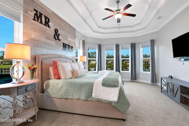 bedroom with carpet flooring, visible vents, baseboards, ornamental molding, and a raised ceiling