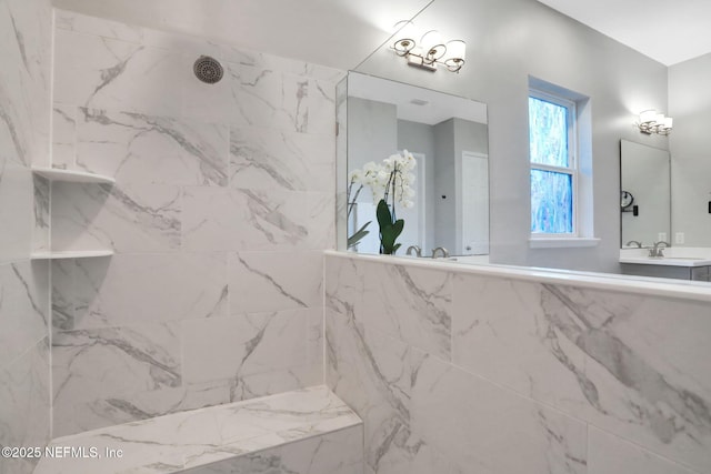 bathroom with tiled shower and a sink