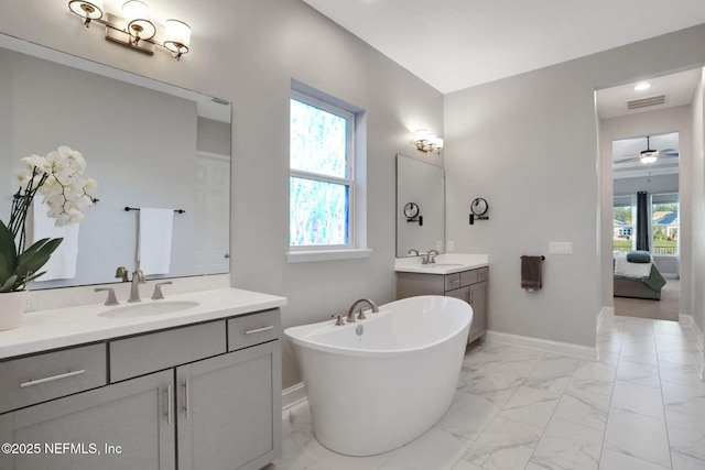 ensuite bathroom featuring marble finish floor, visible vents, a sink, a freestanding tub, and baseboards