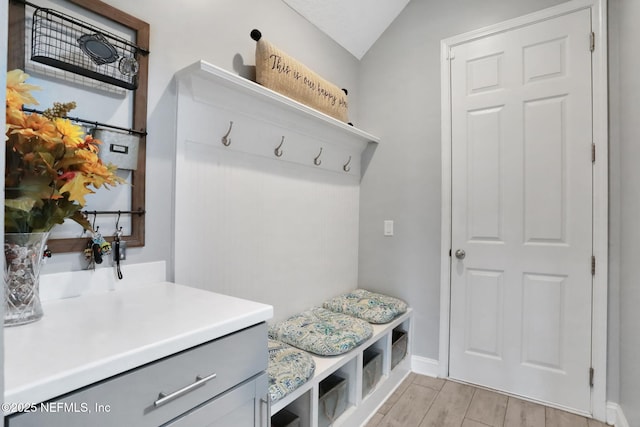 mudroom with vaulted ceiling, light wood-style flooring, and baseboards