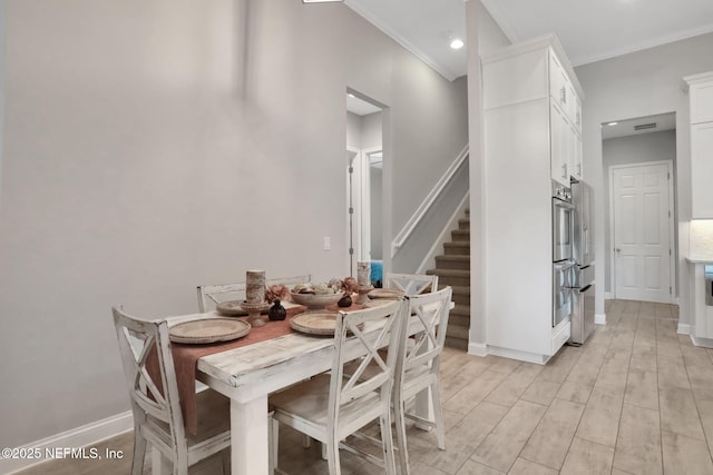 dining room featuring stairs, crown molding, baseboards, and light wood-style floors