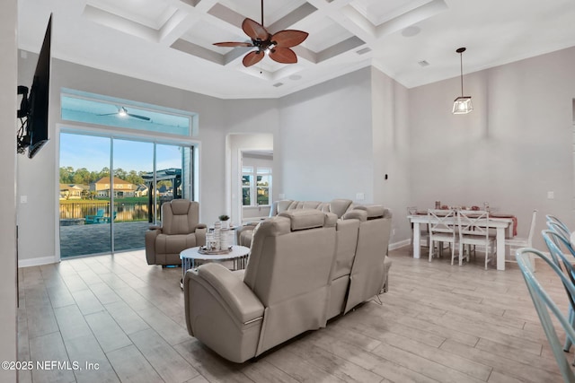 living room with light wood-style floors, baseboards, a high ceiling, and a ceiling fan