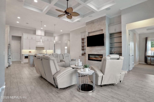 living area featuring light wood-style floors, ornamental molding, and coffered ceiling