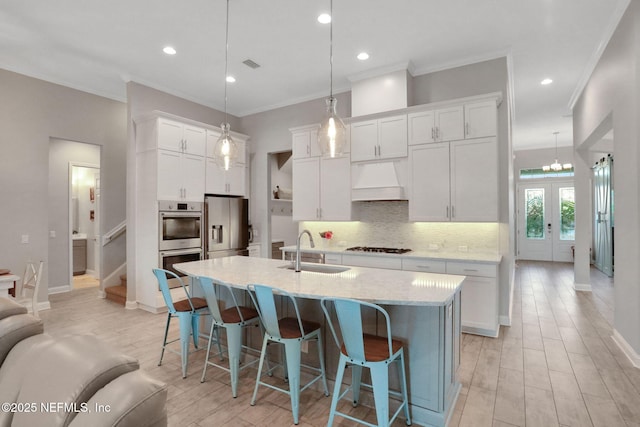 kitchen featuring stainless steel appliances, a sink, white cabinetry, decorative backsplash, and custom range hood