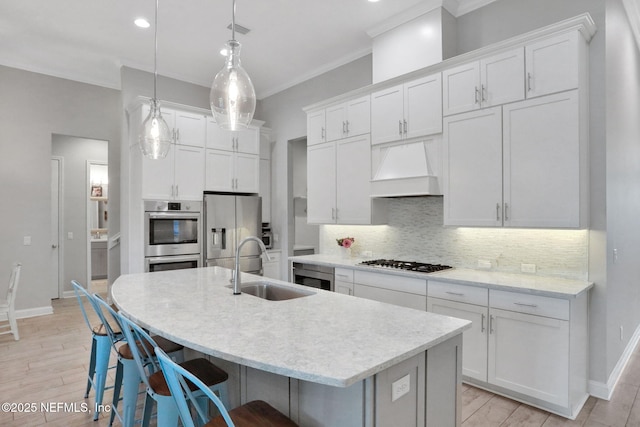 kitchen featuring tasteful backsplash, custom range hood, ornamental molding, stainless steel appliances, and white cabinetry