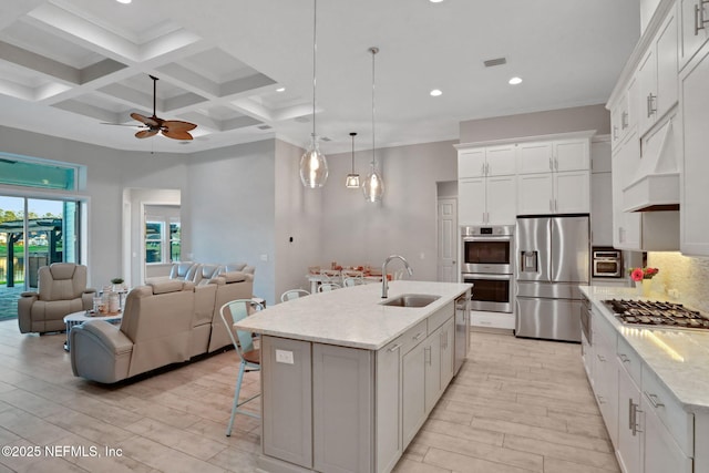 kitchen with a breakfast bar area, tasteful backsplash, appliances with stainless steel finishes, open floor plan, and a sink