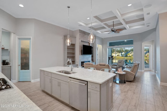 kitchen featuring wood finish floors, appliances with stainless steel finishes, open floor plan, a sink, and coffered ceiling