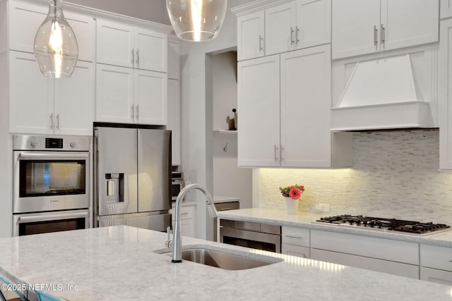 kitchen featuring appliances with stainless steel finishes, a sink, white cabinetry, and custom range hood