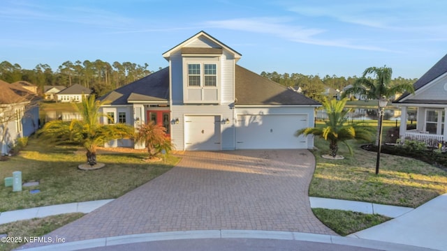 view of front of property with a front yard, decorative driveway, and an attached garage