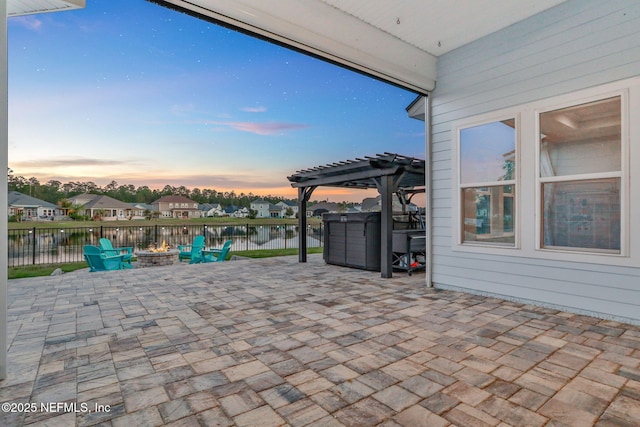 patio terrace at dusk featuring a fire pit, fence, and a pergola