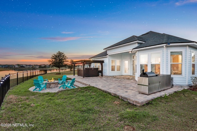 back of house at dusk featuring a patio, fence private yard, a fire pit, a lawn, and a pergola