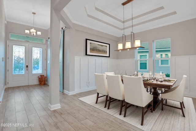 dining space with crown molding, a decorative wall, wood finished floors, and french doors