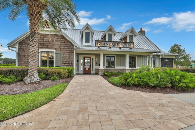 view of front of home featuring a standing seam roof, a chimney, and metal roof