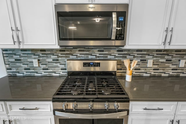 kitchen with stainless steel appliances, tasteful backsplash, dark countertops, and white cabinets