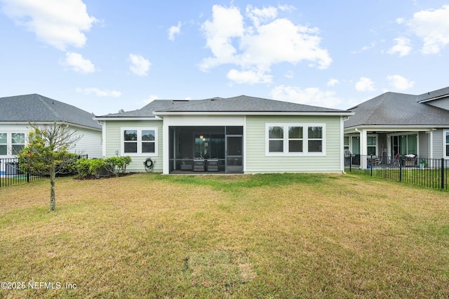 rear view of house featuring a yard, fence, and a sunroom