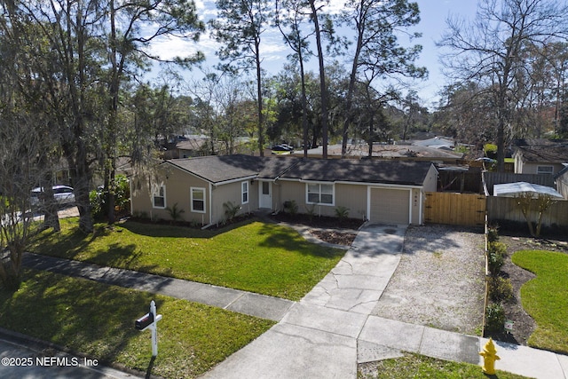 ranch-style home featuring driveway, an attached garage, fence, and a front yard