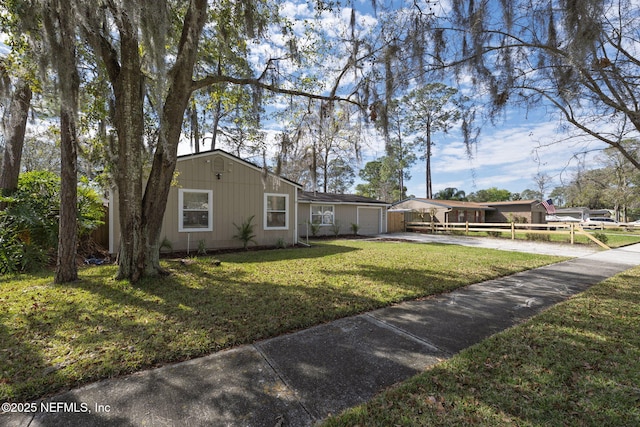 ranch-style house featuring a front yard, concrete driveway, and an attached garage