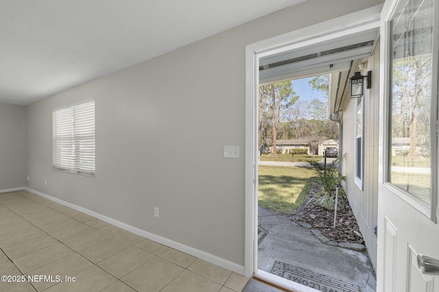 doorway with baseboards, a wealth of natural light, and light tile patterned flooring