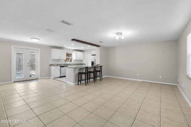 kitchen featuring a kitchen bar, visible vents, stainless steel appliances, and open floor plan