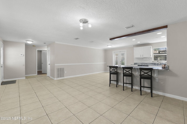 kitchen with tasteful backsplash, visible vents, a peninsula, and a breakfast bar area