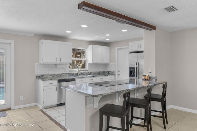 kitchen with stainless steel appliances, white cabinets, backsplash, and light stone countertops