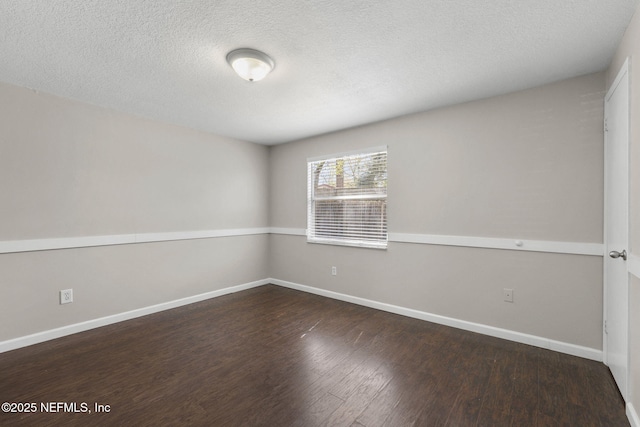 spare room featuring a textured ceiling, baseboards, and wood finished floors