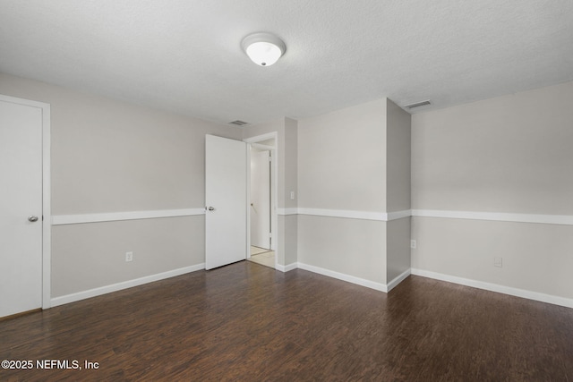 unfurnished room featuring a textured ceiling, wood finished floors, visible vents, and baseboards