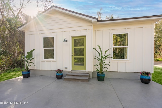 back of house featuring board and batten siding, entry steps, and a patio