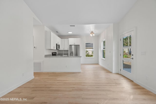 kitchen featuring a peninsula, visible vents, appliances with stainless steel finishes, and white cabinets